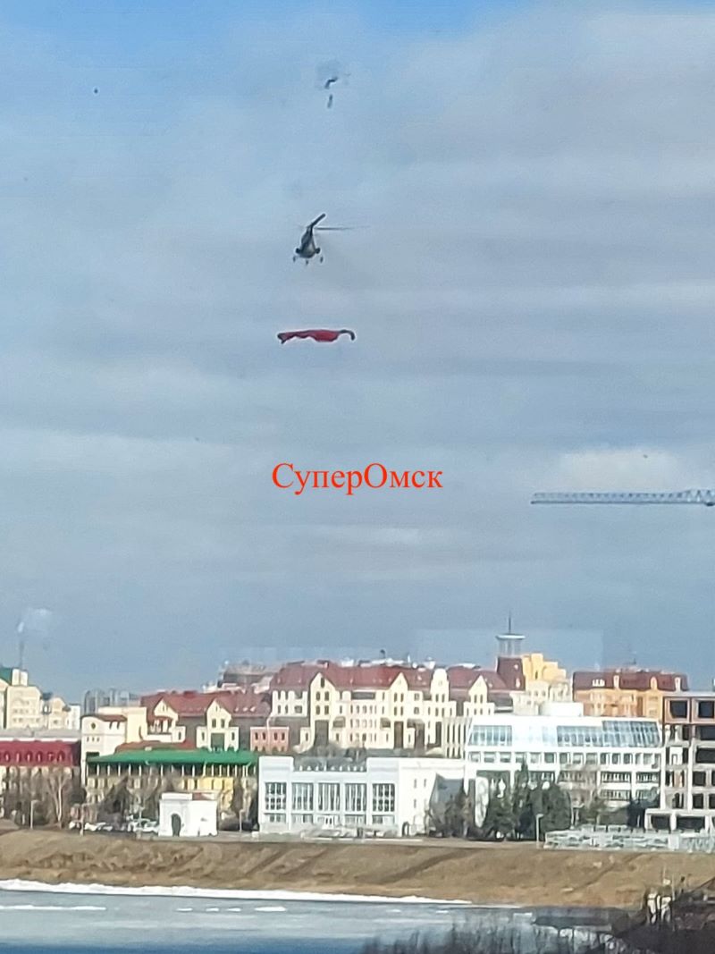 Над центром Омска пролетел вертолет с красным флагом Над центром Омска пролетел вертолет с красным флагом